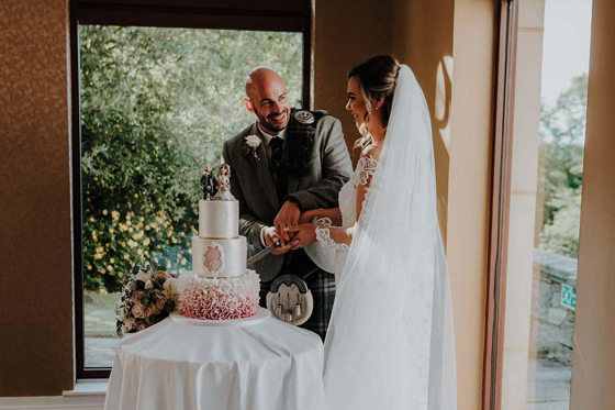 Bride and groom cutting cake and smiling